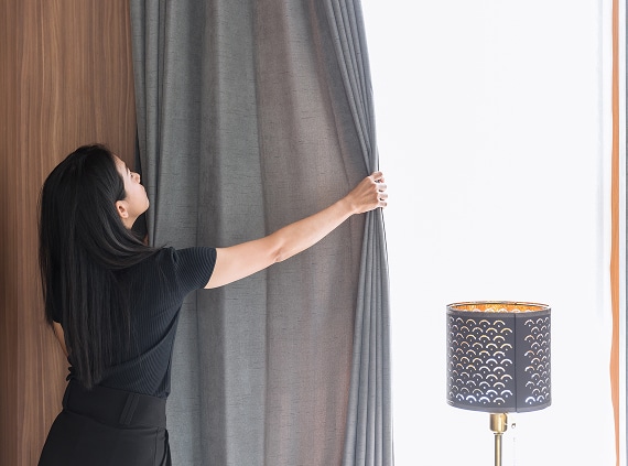 woman opening curtains
