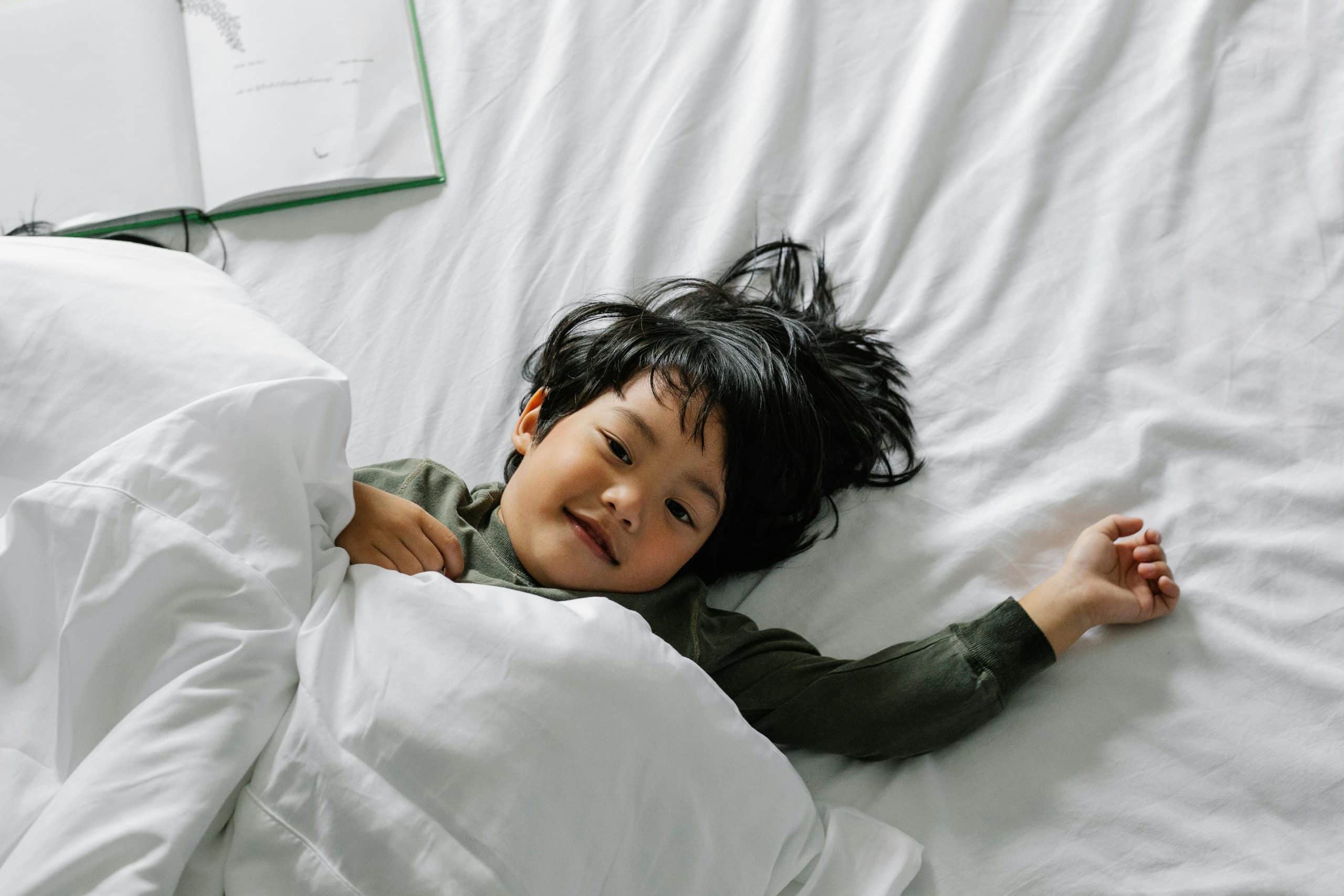 Happy child resting on a freshly cleaned mattress after Chem-Dry Malaysia’s deep cleaning and dust mite allergen treatment